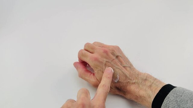 primo piano di mano maschile con dito che distribuisce uniformemente una crema sul dorso della mano