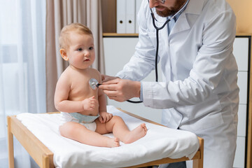 Doctor holding a stethoscope and listening to the babys heartbeat