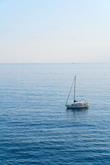 A serene, tranquil sailboat slowly gliding gracefully over the calm, beautiful ocean waters on a...