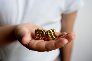 Hand holding gold dice close up