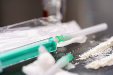 Needle and substances on a surface in a dimly lit room, illustrating drug use and addiction issues