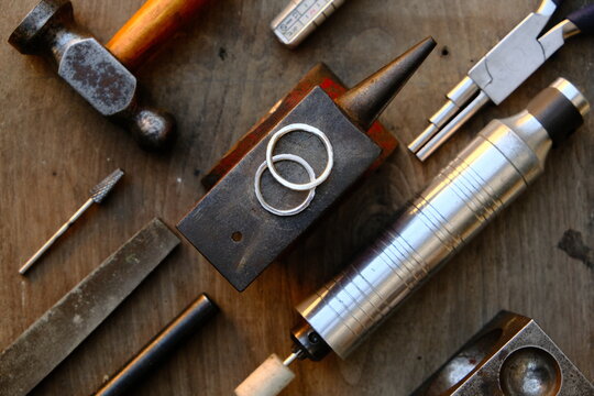 Jeweler's workplace. Top view of jeweler's workbenche with different tools on a wooden table with wedding rings . Goldsmith concept background