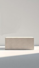 a clean, minimally designed image features a rectangular block placed on a surface against a flat backdrop. the block has a subtly textured surface, appearing almost like plaster or concrete