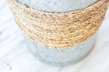 Fototapeta premium Galvanized metal bucket wrapped with brown jute rope. Isolated on white background, perfect for gardening, storage, or rustic decor concepts.