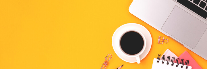 Banner with stationery, laptop and cup of coffee on a yellow background.