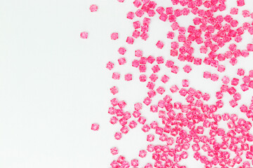Square pink acrylic beads scattered on a blue background with place for text.