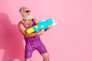 Photo of charismatic elderly cool man serious have fun play watergun wear leopard print overall...