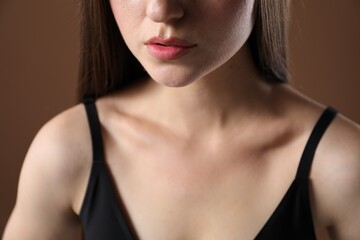 Woman with beautiful collarbone on brown background, closeup