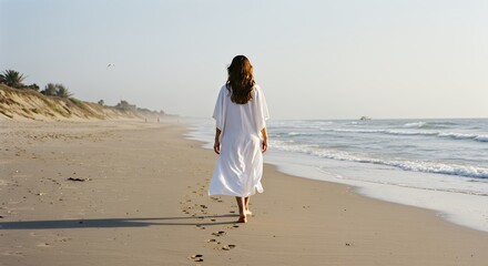 Woman Walking Along Beach with Footprints Towards Ocean Calm Day