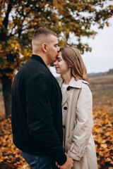 Obraz premium Romantic couple embracing under an autumn tree. Lovers stand among fallen yellow leaves, enjoying a tender moment in nature. Romantic moment surrounded by nature and fallen leaves. vibrant autumn tree