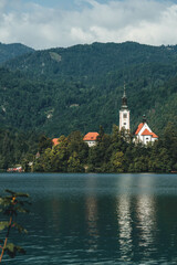 church on the lake with water reflections and mountains green around