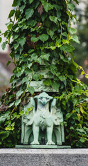 tiny statue of dragon in cooper over green leaves in the city
