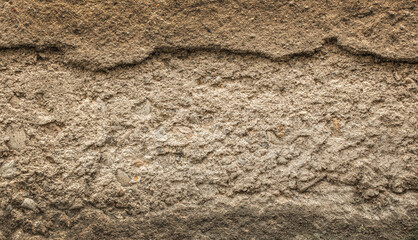 Rough textured earth wall surface showing layers of soil and sediment for background