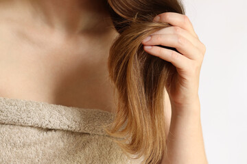 Obraz premium Dry hair ends. Girl examines her hair, close-up. Woman holds a lock of hair with dry, split ends in her hand. Hair care concept. Beauty and health. Hair care problems, vitamin deficiency