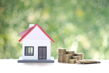Mortgage,Model house and stack of coins money on natural green background,Business investment and real estate concept