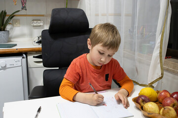 Young child drawing on notebook at home doing homework