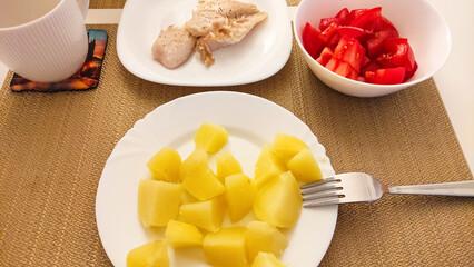 Healthy lunch with boiled potatoes, chicken breast and tomatoes with prague coaster