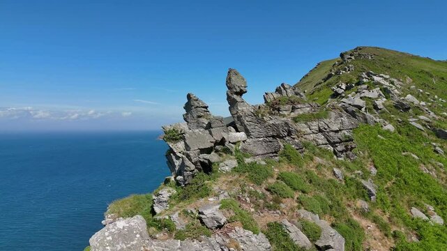 Drone view of rocky cliff covered with green overlooking sea at the Valley of the rocks in Devon