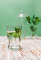 A glass with fresh mint leaves water on a table on a green background with copy space. Health benefits of peppermint water  concept.