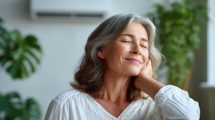 Older woman with closed eyes smiling, relaxed and content at home. Concept of inner peace and wellness for senior health.