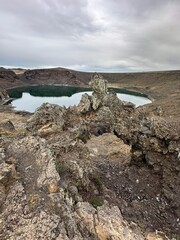 A stunning natural lagoon formed inside the crater of an ancient volcano, surrounded by dark volcanic rock. This unique geological landscape showcases raw natural beauty and dramatic terrain, perfect 