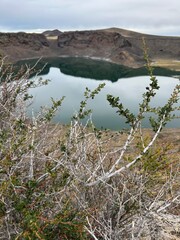 A stunning natural lagoon formed inside the crater of an ancient volcano, surrounded by dark volcanic rock. This unique geological landscape showcases raw natural beauty and dramatic terrain, perfect 