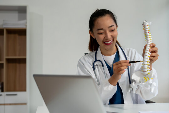 Doctor explains spine surgery using anatomical model in medical office. - Powered by Adobe