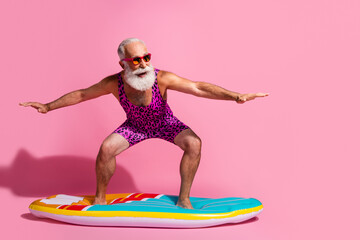 Photo of cheerful positive optimistic pensioner wear swimsuit resort surfing riding wave isolated...