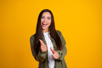 Happy young woman with long brunette hair making fun gestures on a vibrant yellow background...