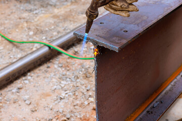 Welder uses torch to cuts metal beams at construction site in , sparks flying