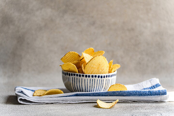 Close-up of a Bowl with homemade potato crisps on a folded tea towel