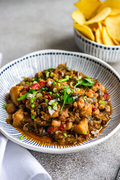 Close-up of a Traditional Georgian chicken and tomato chakhokhbili dish with a bowl of ridged potato crisps