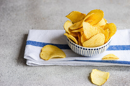 Close-up of a Bowl with homemade potato crisps on a folded tea towel