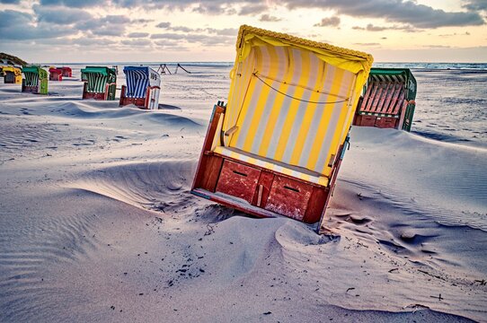 Traditional Beach chairs on a sandy beach displaced during a storm, Juist, East Frisia, Lower Saxony, Germany