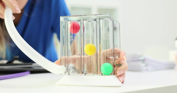 Doctor grips triflow spirometer to assess lung capacity. Physician explains importance of using triflow spirometer during respiratory rehabilitation