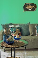 Marine style in the apartment interior - a sofa with pillows and a table with shells and fish figures.