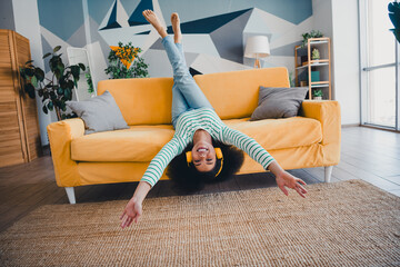 Young woman relaxed upside down on a stylish sofa in a cozy living room with modern decor and...