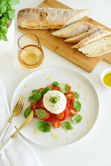 Fresh Caprese salad with mozzarella, tomatoes, and basil, served with bread.