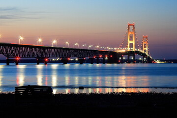 Suspension bridge glowing over calm water at twilight