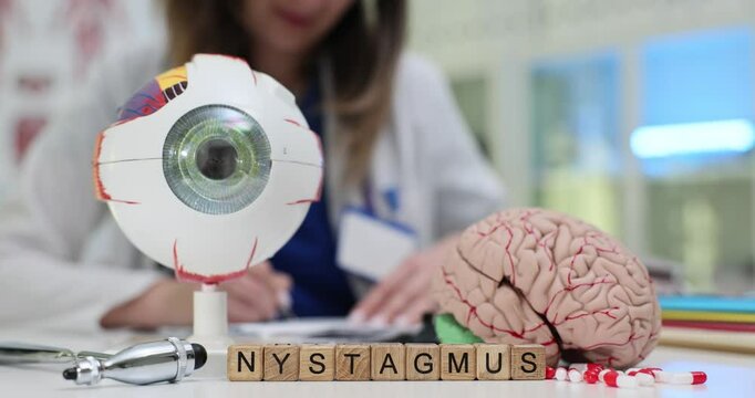 Word Nystagmus of wood blocks with brain and eyeball models against doctor. Female medic checks neurological aspects of involuntary eye movements