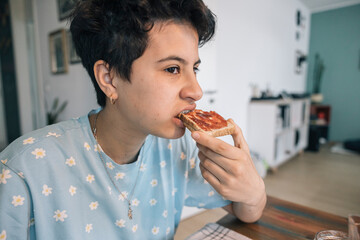Teenager girl enjoying breakfast with jam and toast in the morning