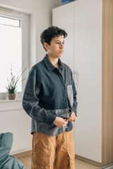 Teenager girl buttoning shirt in the morning routines at home