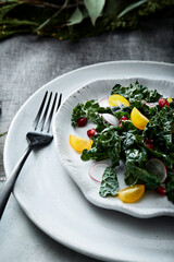 Kale salad with tomatoes, radish, and pomegranate on plate