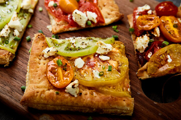 Tomato tart slices with feta cheese and herbs on wood board