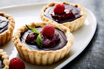 Chocolate tart with fresh raspberries on white scalloped plate