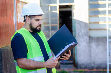 Portrait of male factory or industry worker wearing safety gear holding a folder or a binder outdoor.Recycle factory concept.Construction site.