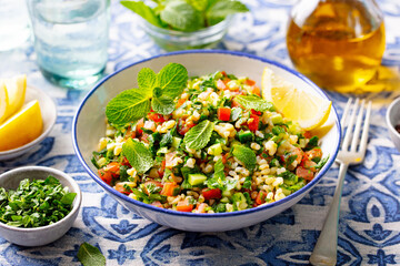 Tabbouleh salad in a bowl. Blue background. Close up.