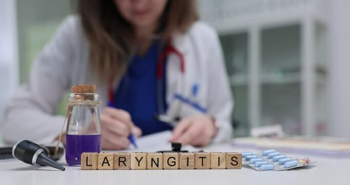 Doctor works diligently with documents examining Laryngitis on wooden blocks in medical office. Medical concept illustrating laryngitis treatment