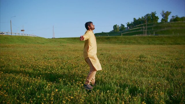 Joyful Indian male in traditional kurta running freely through golden flower meadow, embodying carefree spirit and cultural vibrancy under bright blue sky