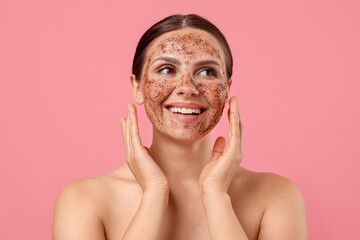 Smiling woman with body scrub on her face against pink background